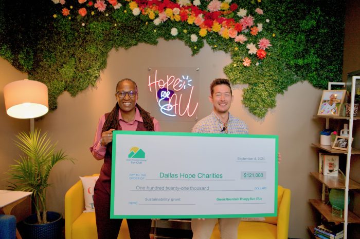 Chief Executive Officer of Dallas Hope Charities, Tamika Perry, and Green Mountain Sun Club Representative, Johnny Richardson, stand in the lobby of Dallas Hope Charities office holding a large check in the amount of $121,000 for the Sustainability Project